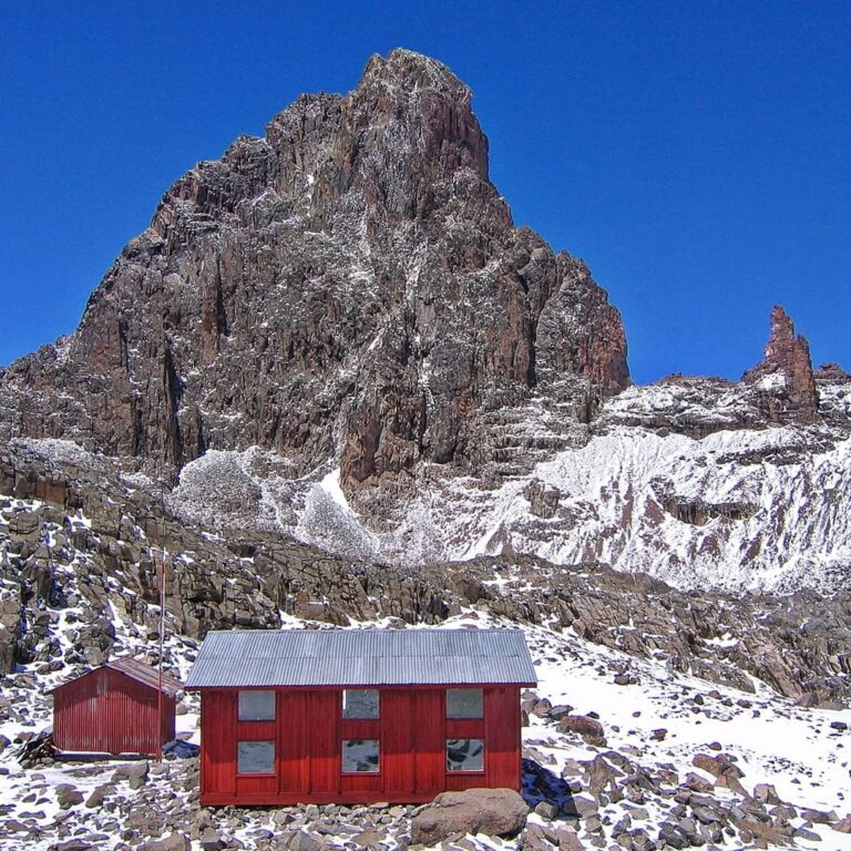 The red Austrian Hut beneath Mount Kenya's snowy central rock peaks