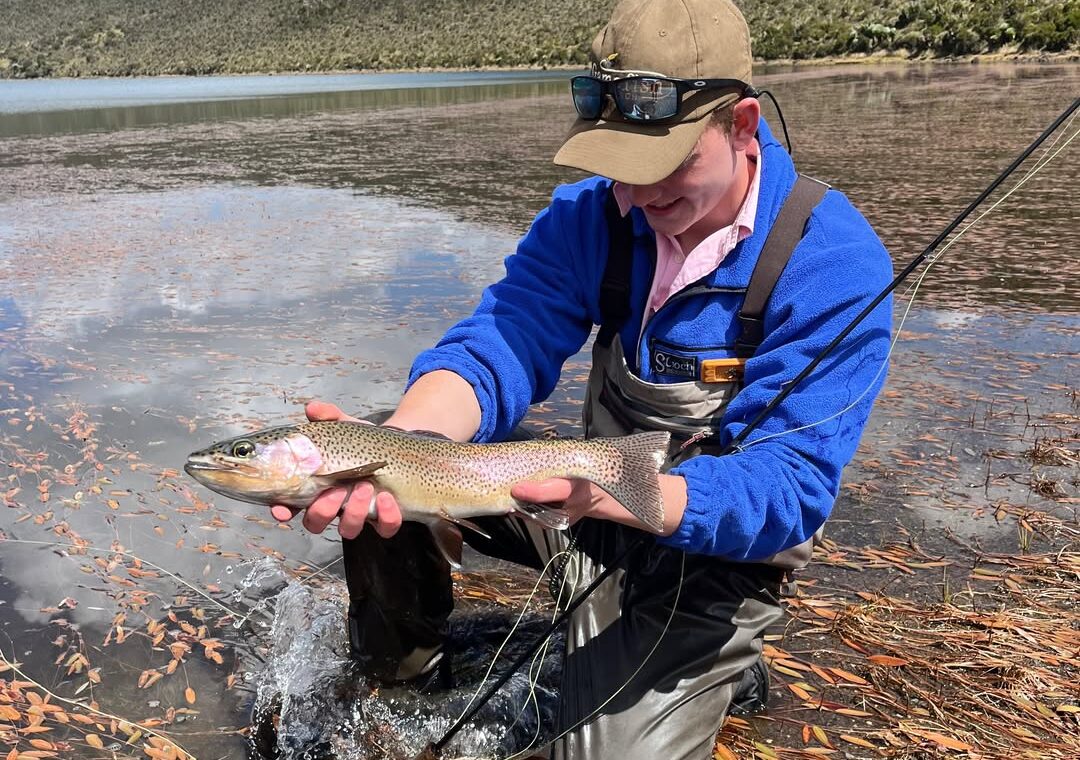 Wilderness Alternative guest holding a trout while fly fishing at a Mount Kenya lake