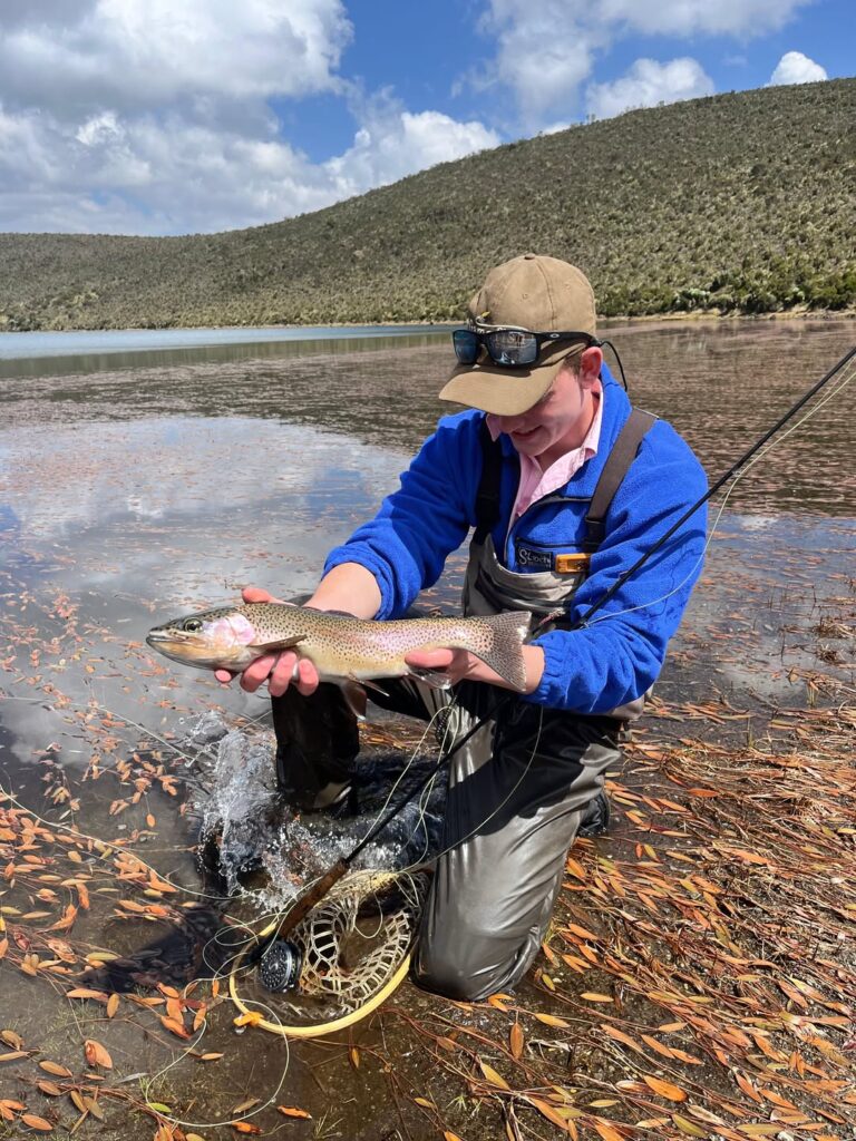 Wilderness Alternative guest holding a trout while fly fishing at a Mount Kenya lake