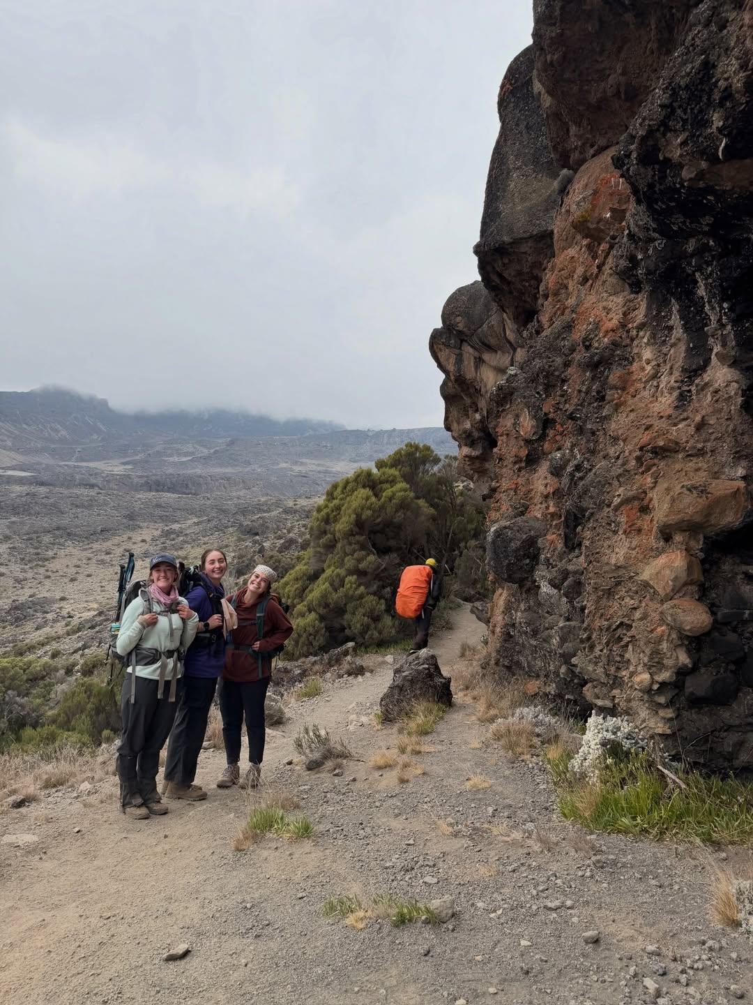 WAE guests hiking beneath volcanic cliffs in Kilimanjaro’s high alpine zone