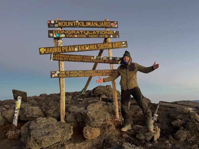 Kilimanjaro climber beside the Uhuru Peak 5,895 m summit sign