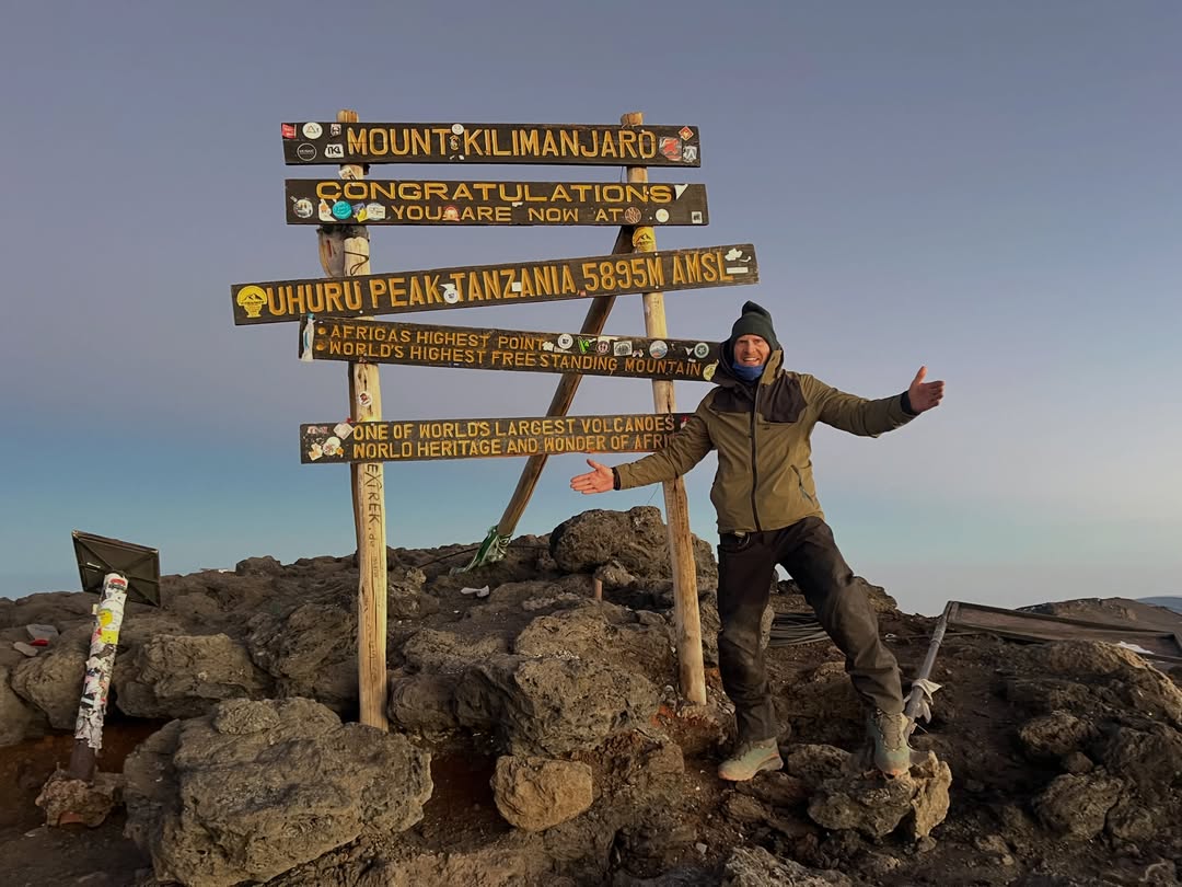 Kilimanjaro climber beside the Uhuru Peak 5,895 m summit sign