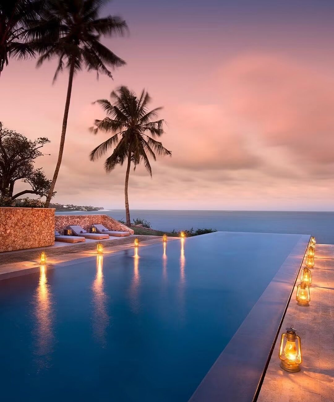 Lantern-lit infinity pool overlooking the Indian Ocean at sunset