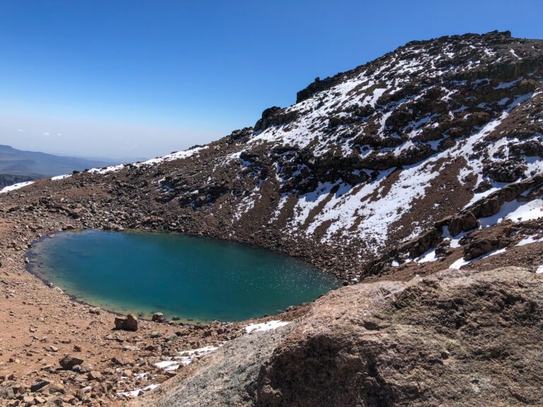 Upper Simba Tarn beneath snow-speckled volcanic slopes on Mount Kenya