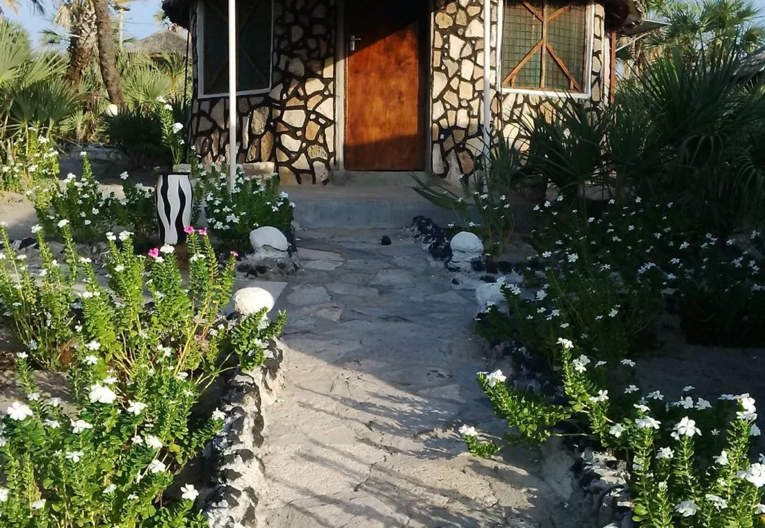 Flower-lined path to a stone cottage at Malabo Resort in Loiyangalani.