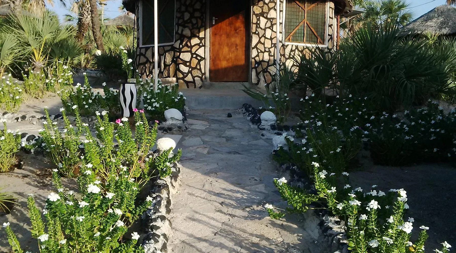 Flower-lined path to a stone cottage at Malabo Resort in Loiyangalani.