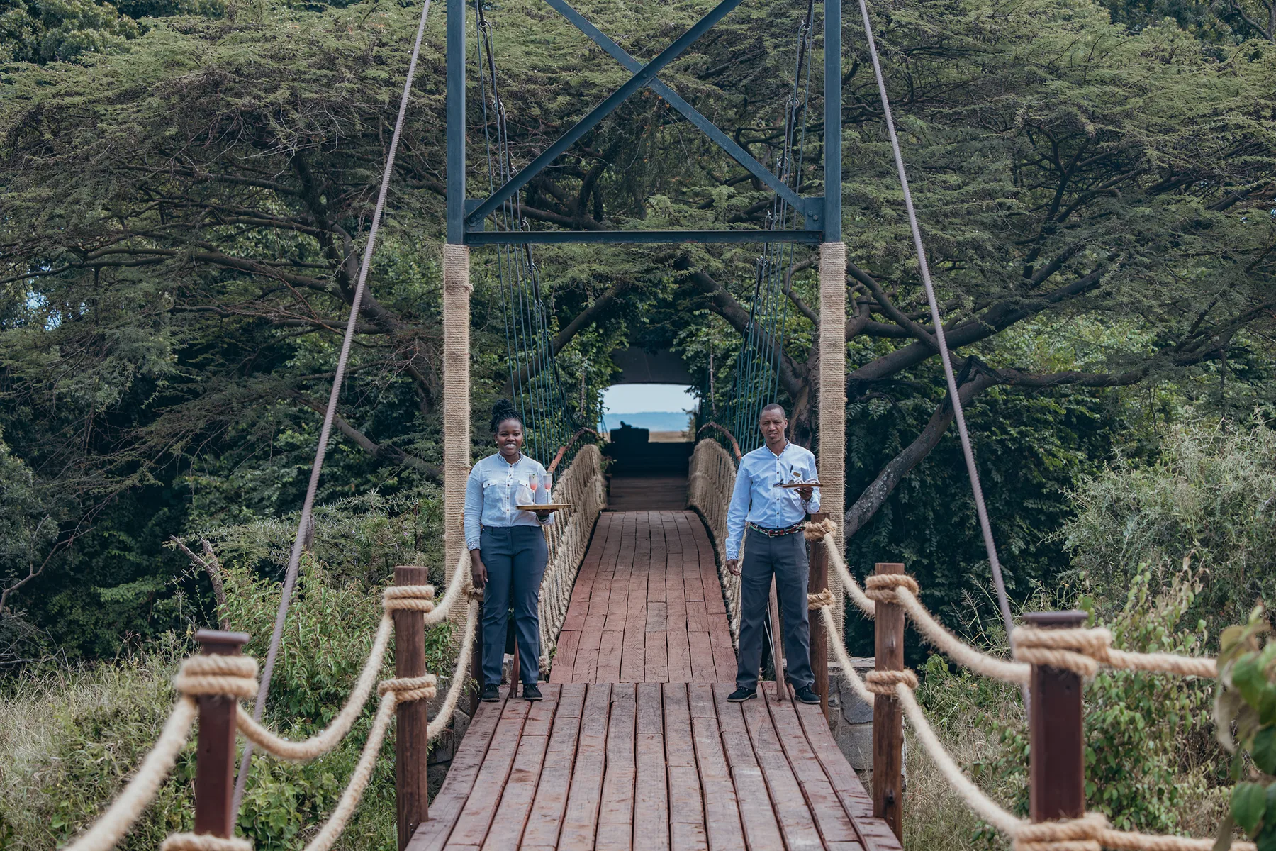 Staff welcoming guests at the suspension bridge entrance to Mara Plains Camp.