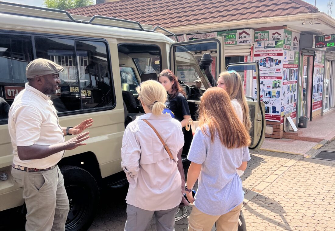 Moses Kironjo speaking with safari guests beside a Land Cruiser before their journey