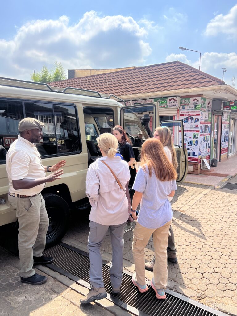 Moses Kironjo speaking with safari guests beside a Land Cruiser before their journey