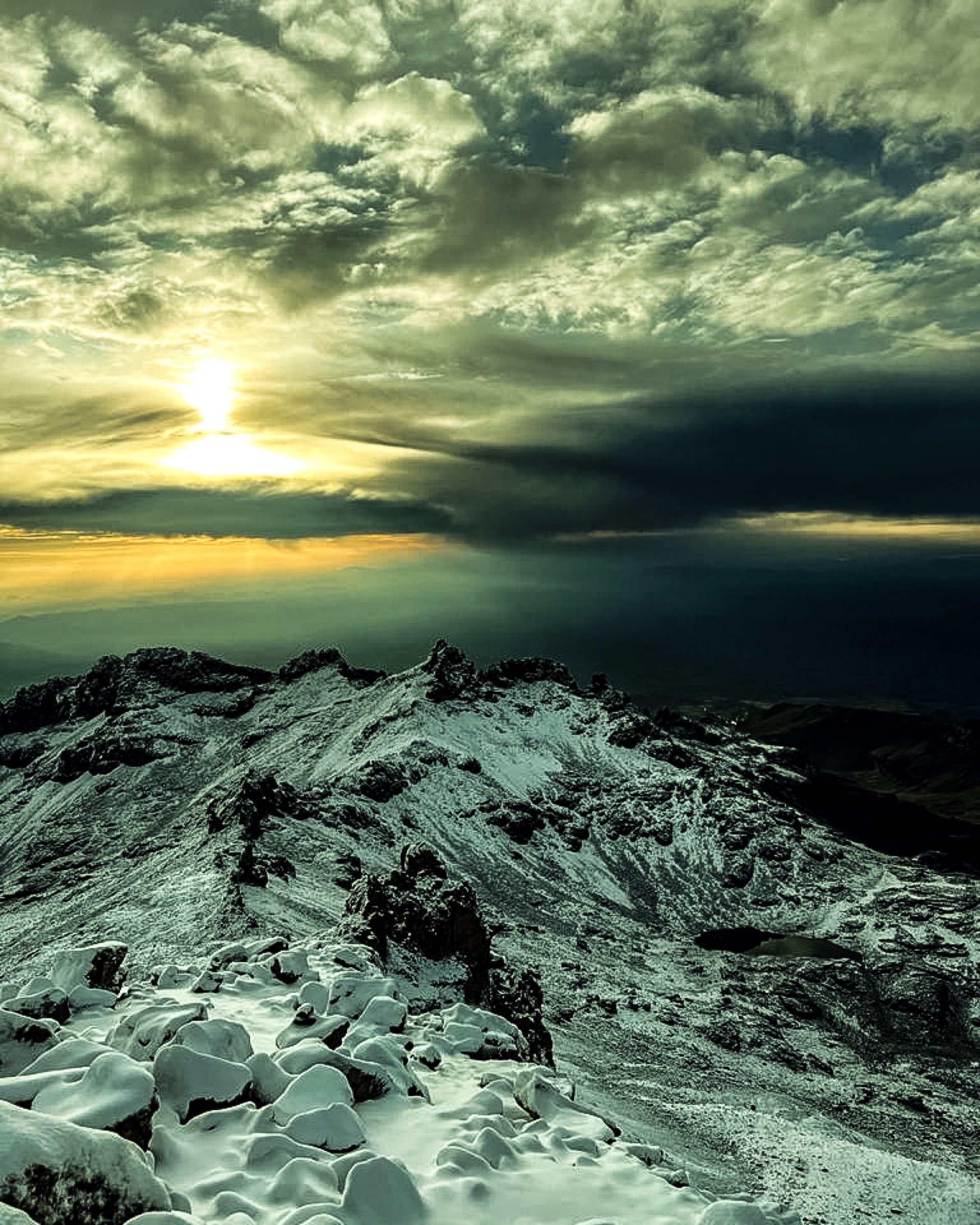 Sunrise breaking through cloud above snow-covered ground on Mount Kenya