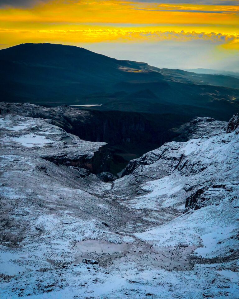 Golden sunrise above a snow-covered Mount Kenya valley seen from Point Lenana