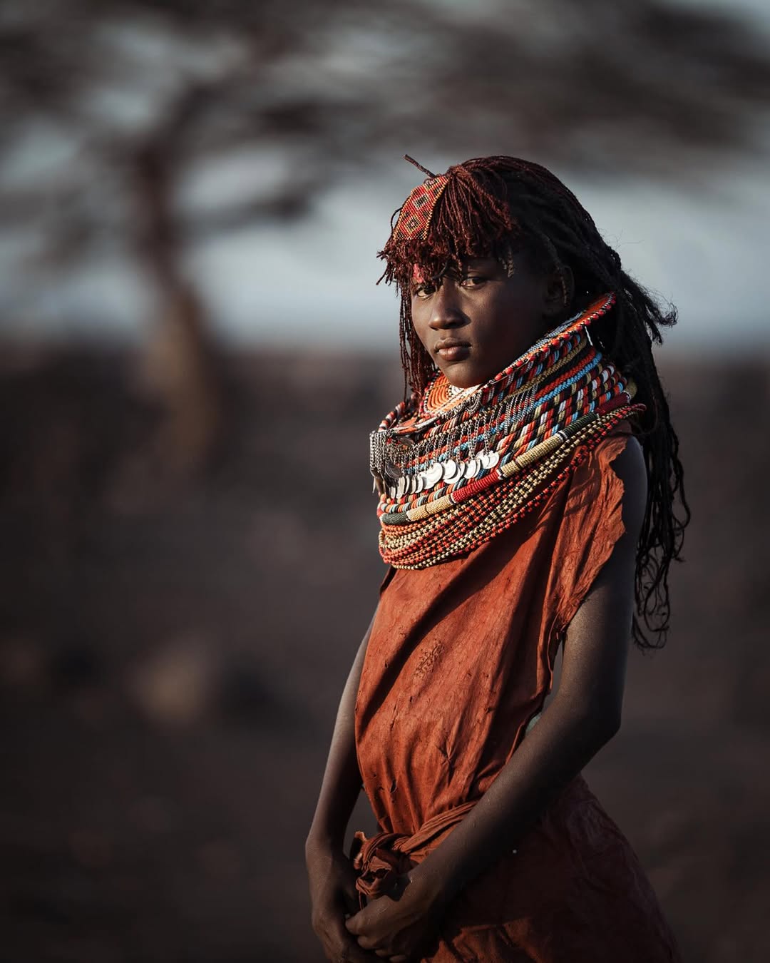 Turkana woman wearing layered beadwork and a red dress in northern Kenya