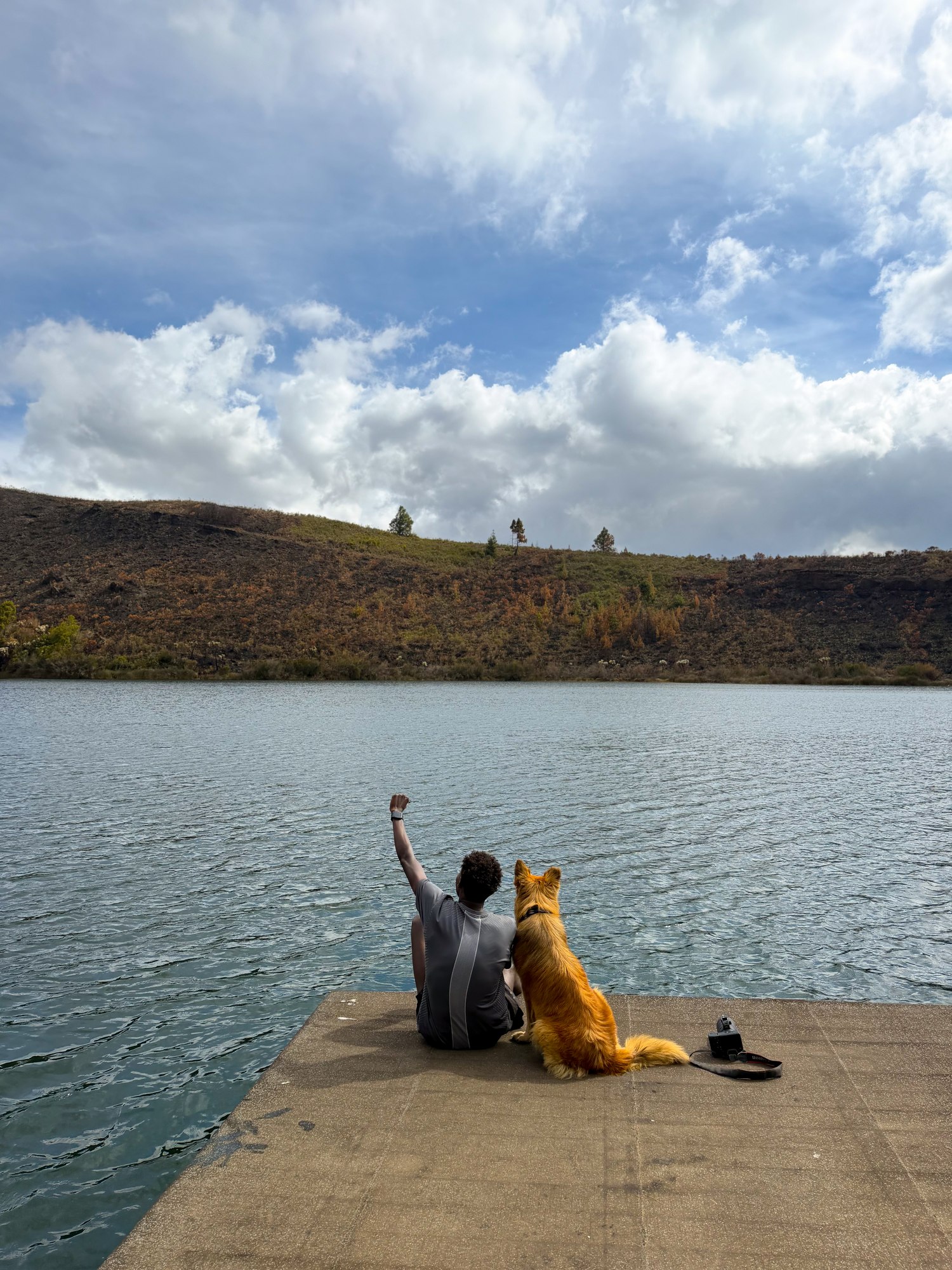 Kennedy Mutuma and his dog sitting on a platform beside Lake Rutundu after walking from the gorge